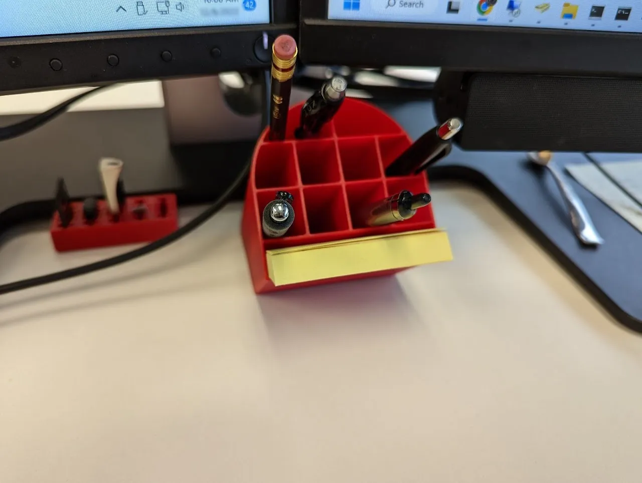 Cốc đựng bút nghiêng đặt dưới màn hình máy tính