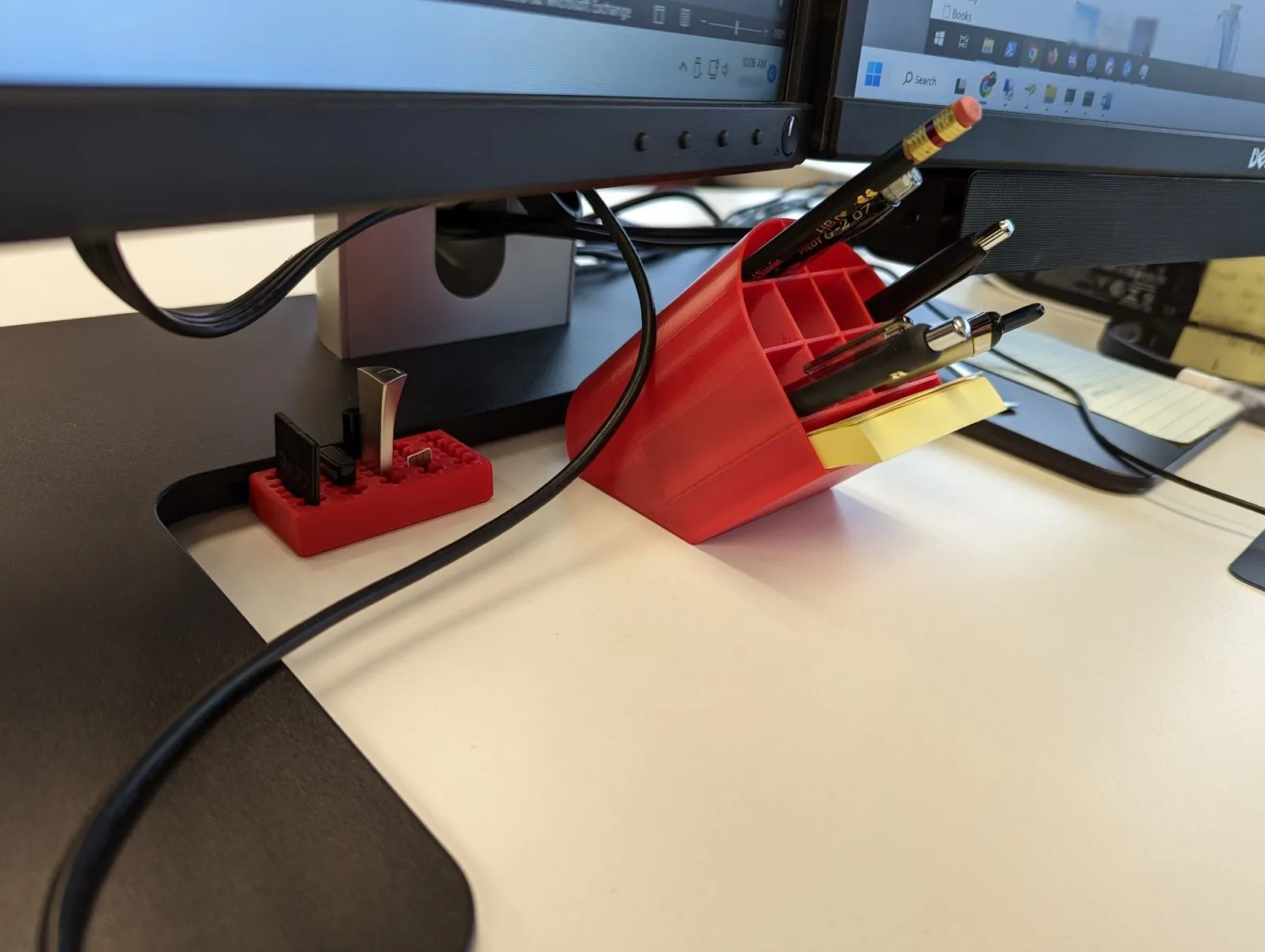 Cốc đựng bút nghiêng đặt dưới màn hình máy tính