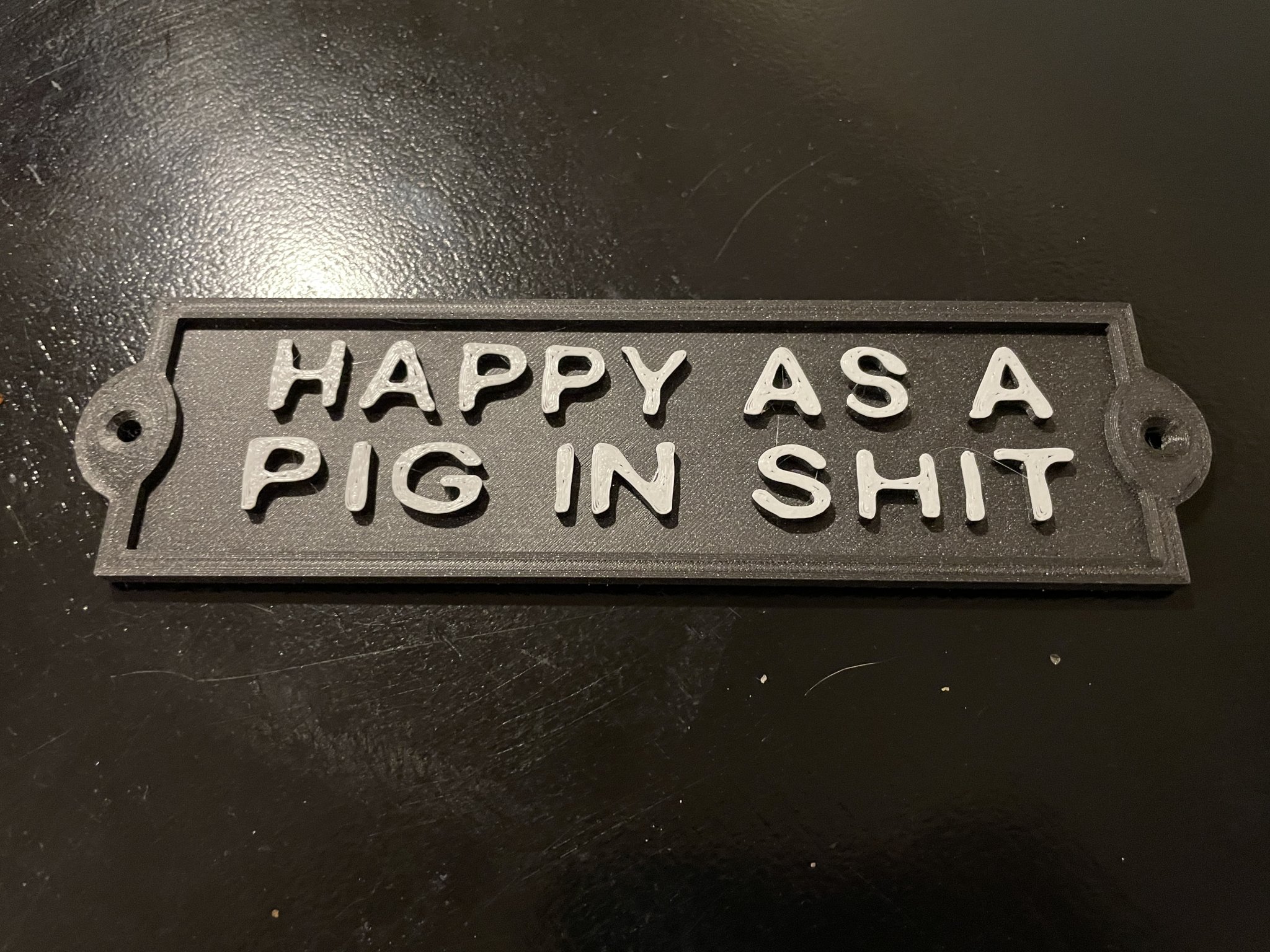 Biển hiệu "HAPPY AS A PIG IN SHIT" cho bàn làm việc