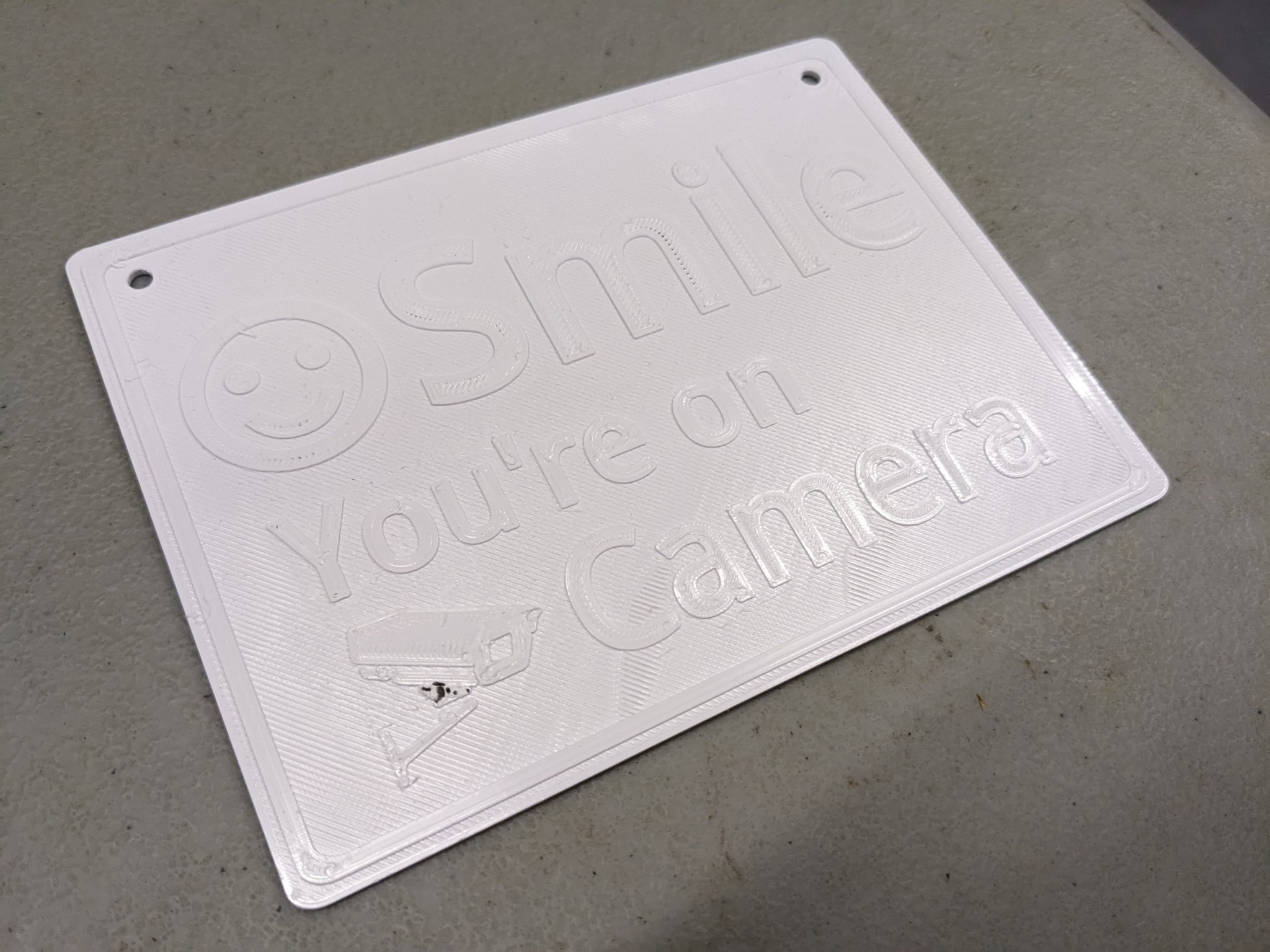 Biển báo "Cười lên, bạn đang ở trên camera" với lỗ vít