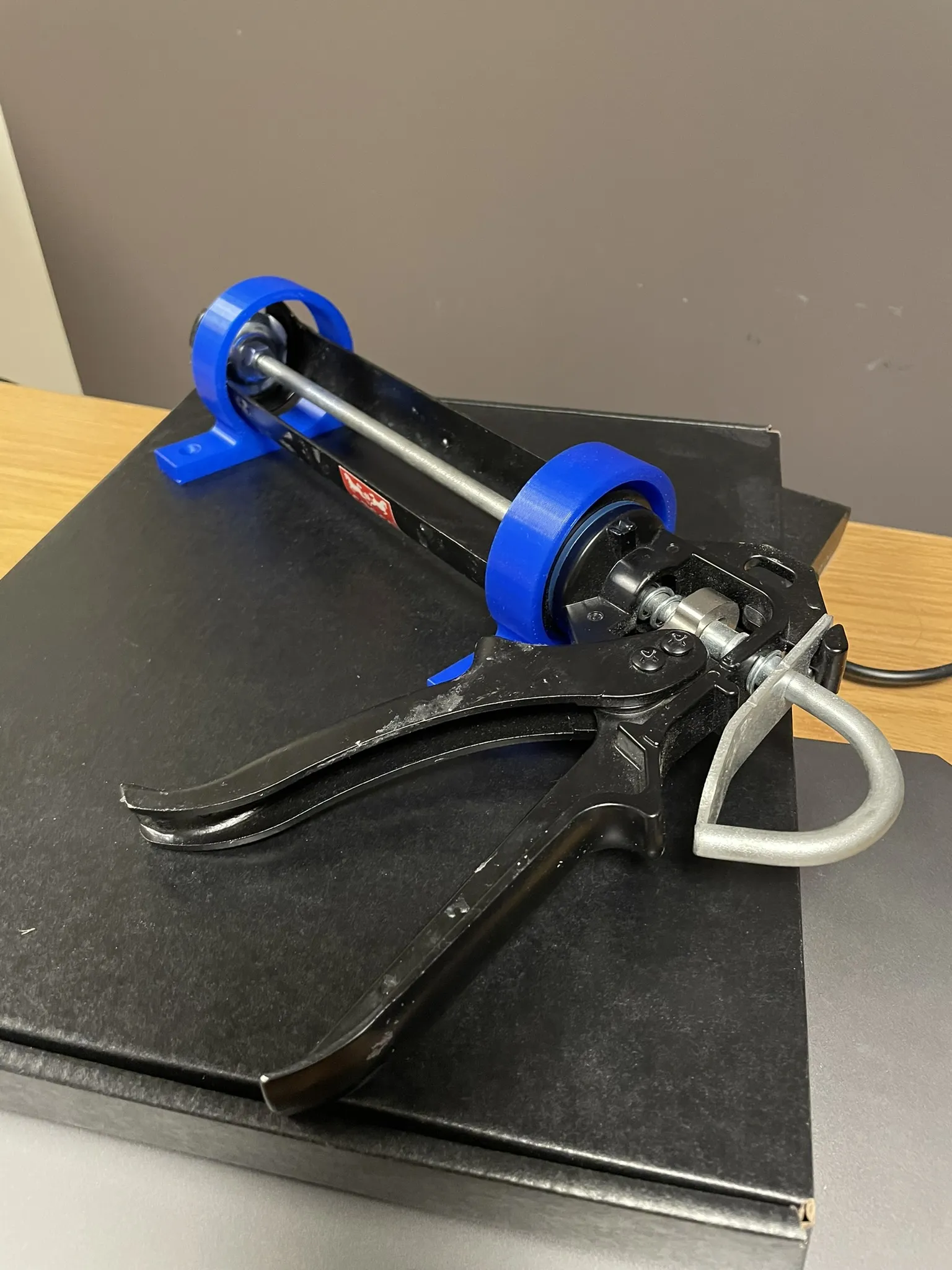 Giá đỡ súng bơm keo gắn kệ